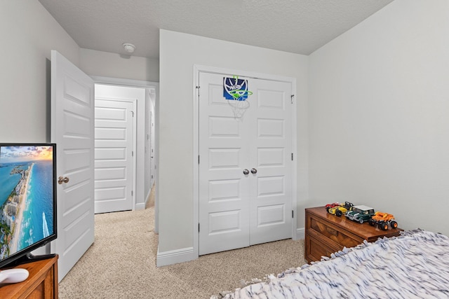 bedroom featuring a textured ceiling, light colored carpet, and a closet