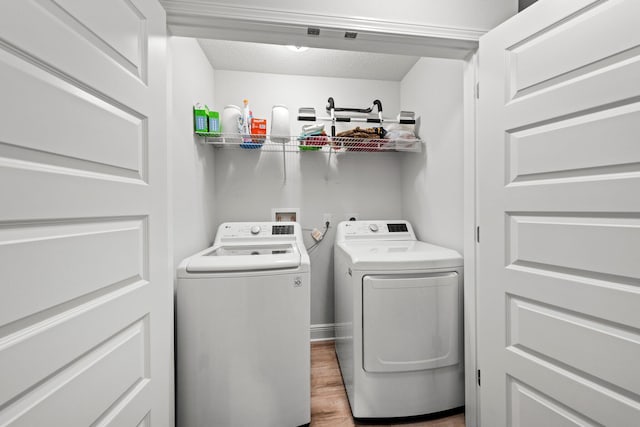 laundry area with washer and clothes dryer and light hardwood / wood-style floors