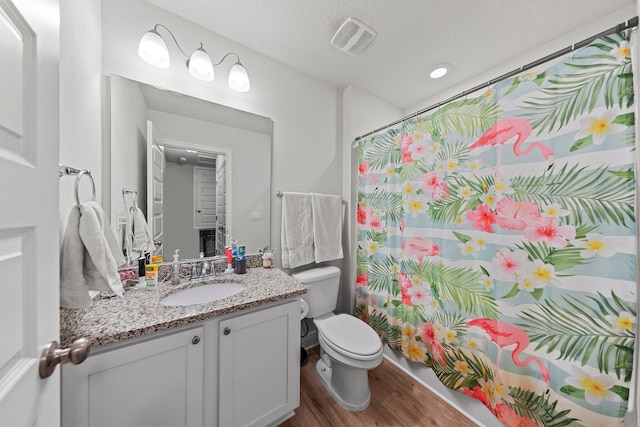 bathroom featuring a textured ceiling, vanity, hardwood / wood-style flooring, toilet, and curtained shower