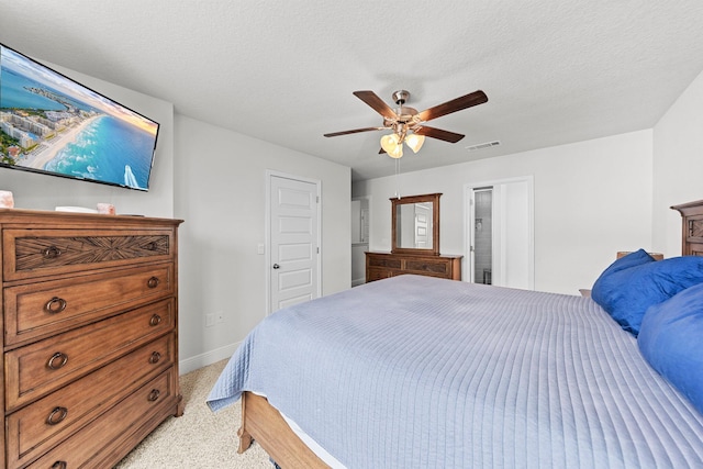 carpeted bedroom with ensuite bath, ceiling fan, and a textured ceiling