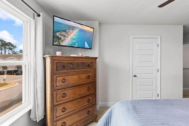 carpeted bedroom with ceiling fan and a textured ceiling