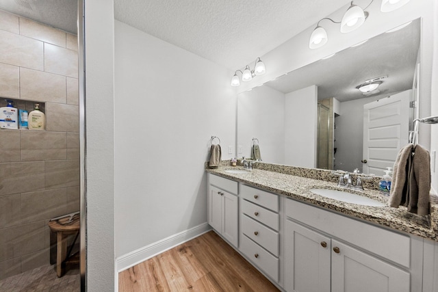 bathroom featuring vanity, a tile shower, a textured ceiling, and hardwood / wood-style flooring