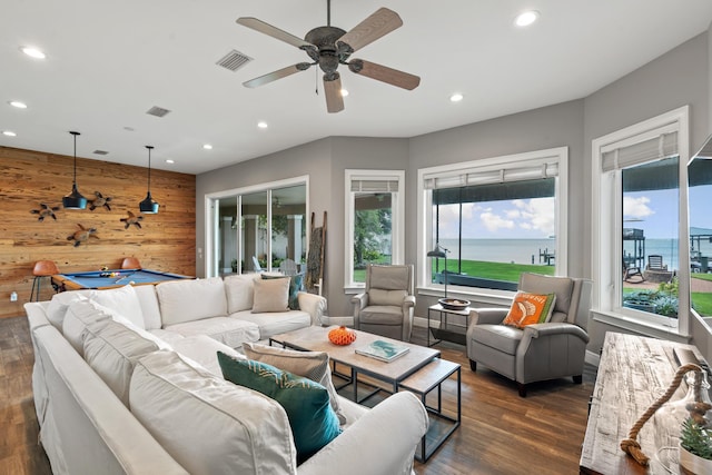 living room featuring dark hardwood / wood-style floors, a water view, wood walls, and billiards