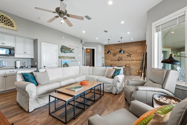 living room with ceiling fan, dark hardwood / wood-style floors, and wood walls