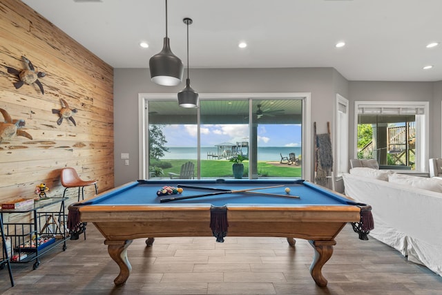 rec room with a water view, pool table, wooden walls, and hardwood / wood-style floors