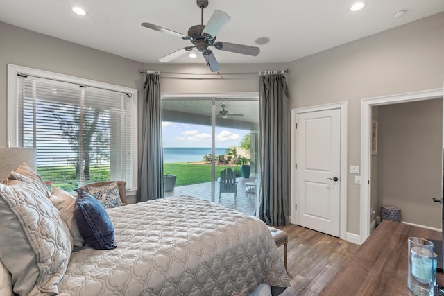 bedroom featuring ceiling fan, a water view, wood-type flooring, and access to outside