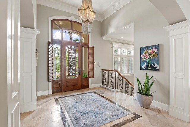 foyer featuring a healthy amount of sunlight, a notable chandelier, crown molding, and decorative columns