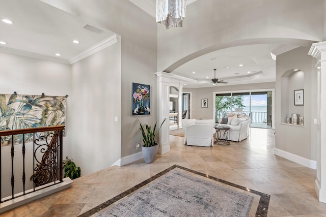 corridor with an inviting chandelier, ornamental molding, ornate columns, and a tray ceiling