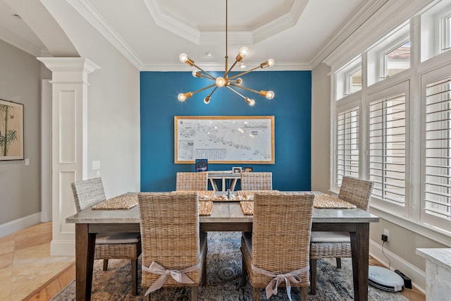 dining area with a tray ceiling, crown molding, ornate columns, and an inviting chandelier