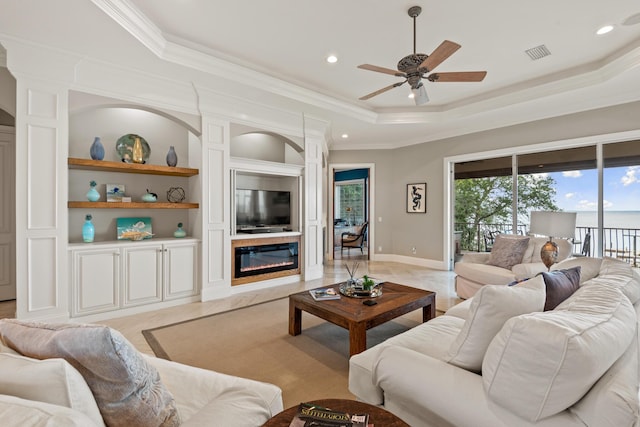 living room featuring a raised ceiling, ceiling fan, built in features, and crown molding