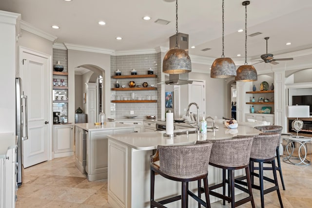 kitchen featuring a large island with sink, pendant lighting, decorative backsplash, a kitchen bar, and sink