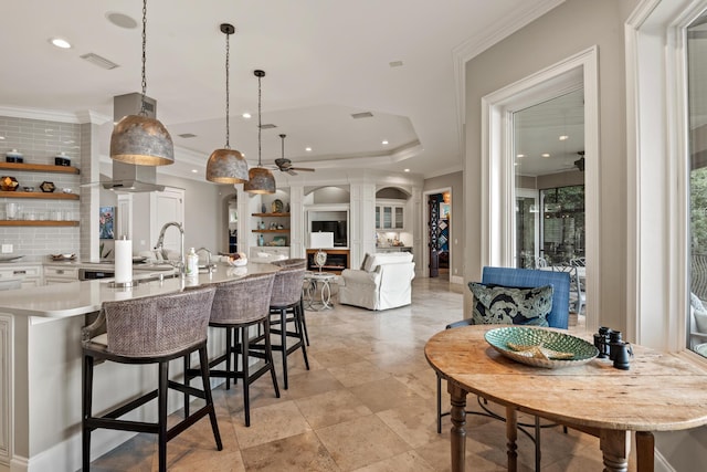 kitchen with ceiling fan, a tray ceiling, white cabinets, and hanging light fixtures