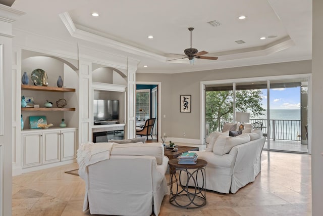 living room featuring ceiling fan, ornamental molding, and a raised ceiling