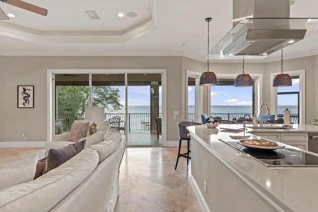 kitchen featuring pendant lighting, a tray ceiling, and a water view