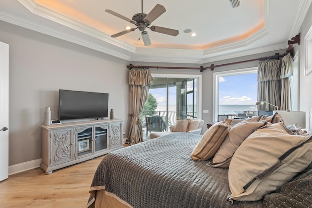 bedroom featuring light hardwood / wood-style floors, access to exterior, ornamental molding, ceiling fan, and a tray ceiling