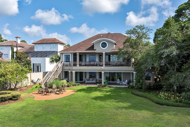 rear view of house with a lawn, a patio area, a balcony, and a lanai