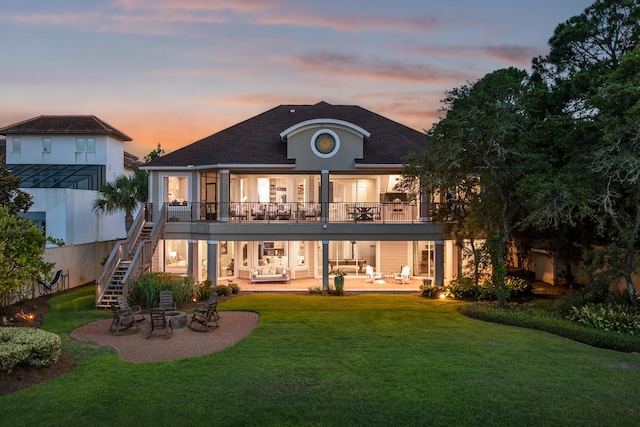 back house at dusk with a patio area and a yard