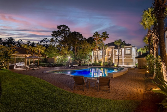 pool at dusk featuring a gazebo, a patio area, and a yard