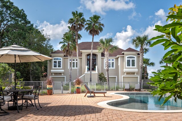 rear view of property featuring a garage, a fenced in pool, and a patio