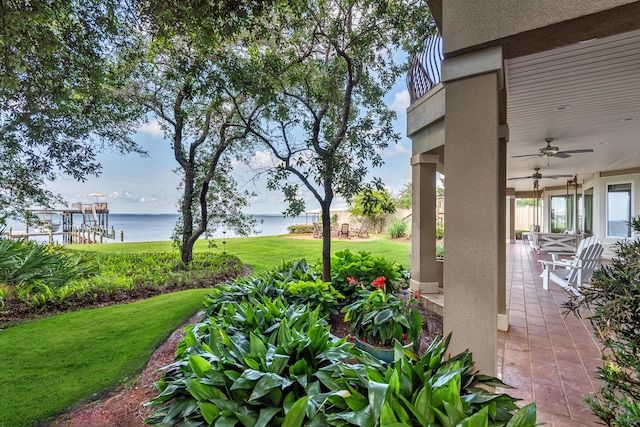 view of yard with ceiling fan, a patio area, and a water view