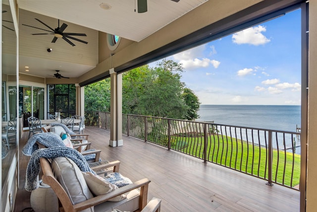 wooden deck featuring ceiling fan, a water view, and a yard