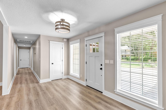 foyer with plenty of natural light, a textured ceiling, and light hardwood / wood-style flooring