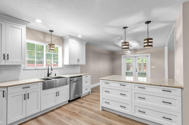 kitchen with dishwasher, sink, backsplash, pendant lighting, and white cabinets