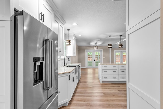 kitchen featuring french doors, high quality fridge, light hardwood / wood-style flooring, white cabinetry, and hanging light fixtures