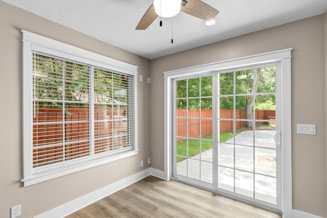 doorway with light wood-type flooring, a textured ceiling, and ceiling fan