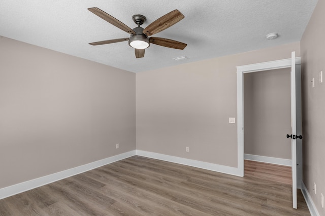 spare room with hardwood / wood-style flooring, ceiling fan, and a textured ceiling