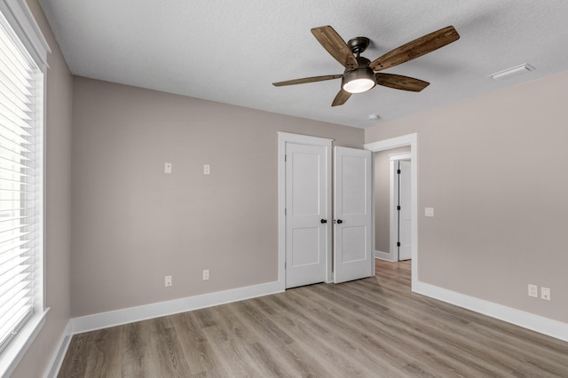 unfurnished bedroom featuring ceiling fan, light hardwood / wood-style flooring, and a textured ceiling