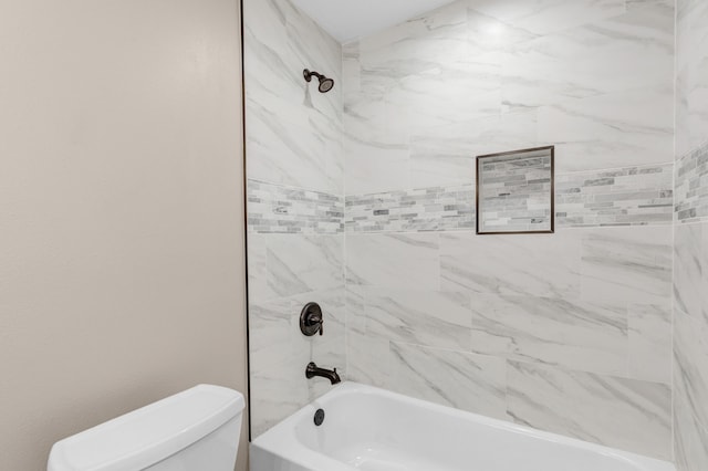 bathroom with toilet and tiled shower / bath