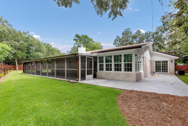 rear view of property with a lawn, a sunroom, and a patio