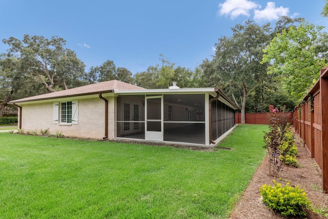 back of property with a sunroom and a yard