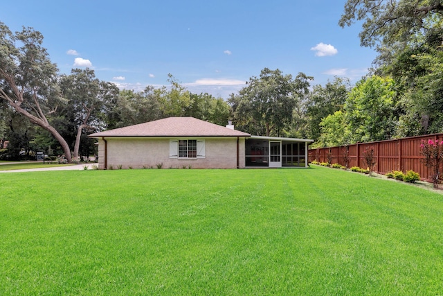 back of house featuring a lawn and a sunroom