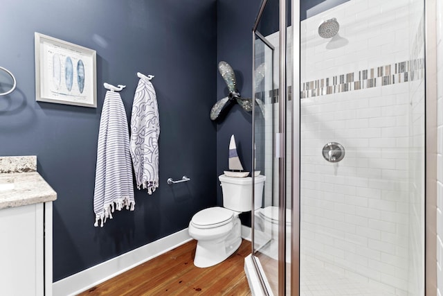 bathroom featuring a shower stall, baseboards, toilet, wood finished floors, and vanity