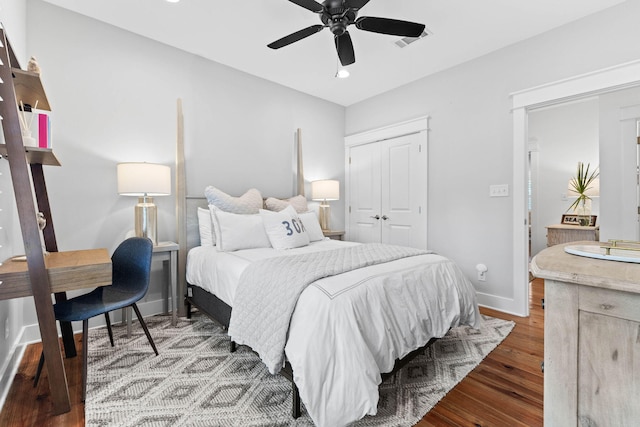 bedroom with wood finished floors, visible vents, baseboards, ceiling fan, and a closet