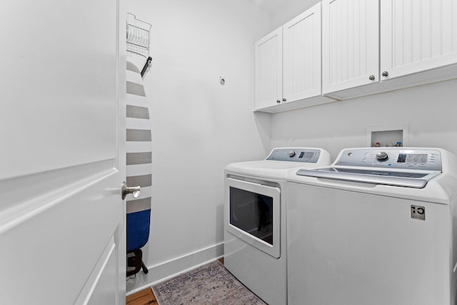 clothes washing area with cabinet space, wood finished floors, baseboards, and separate washer and dryer