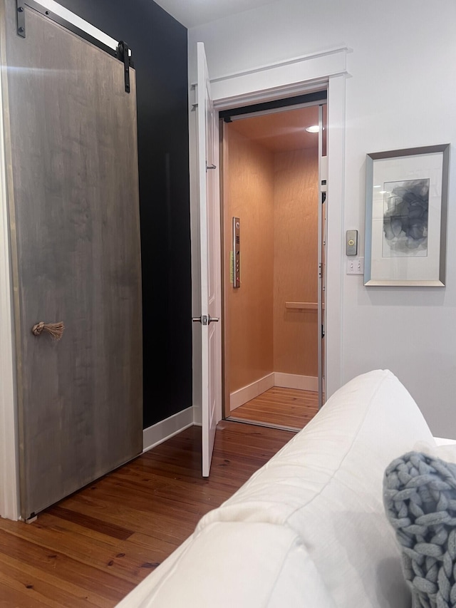 bedroom featuring a barn door and wood finished floors