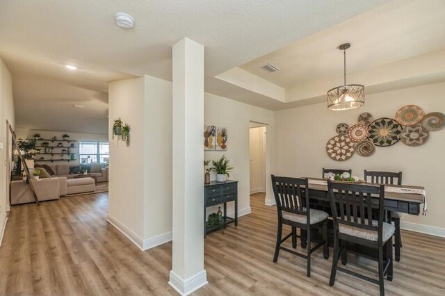 dining room featuring a notable chandelier, hardwood / wood-style flooring, and a raised ceiling