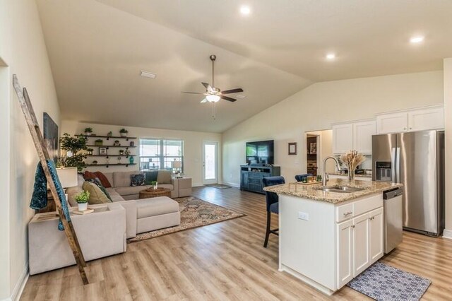 kitchen featuring ceiling fan, light hardwood / wood-style flooring, a center island with sink, stainless steel appliances, and white cabinetry