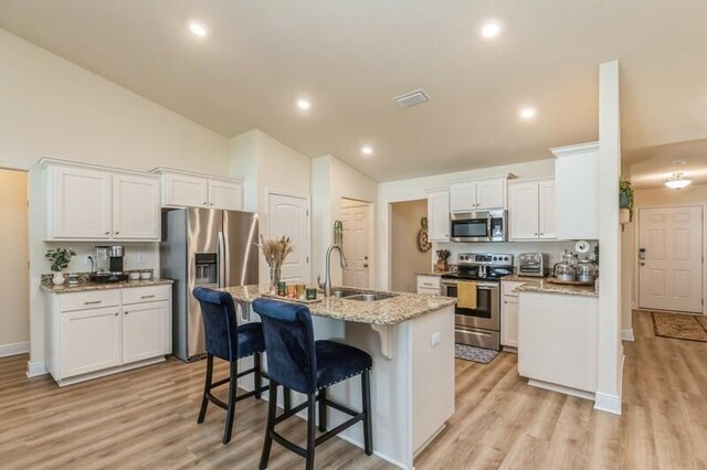 kitchen with light hardwood / wood-style floors, stainless steel appliances, sink, a kitchen island with sink, and white cabinetry