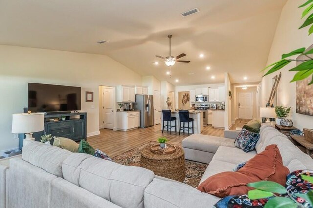 living room featuring high vaulted ceiling, ceiling fan, and light hardwood / wood-style flooring