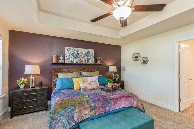 bedroom featuring ceiling fan, a raised ceiling, and light colored carpet