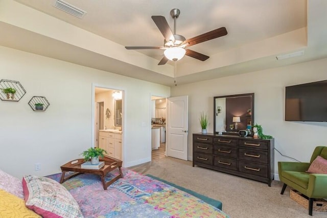 carpeted bedroom with ensuite bath, ceiling fan, and a raised ceiling