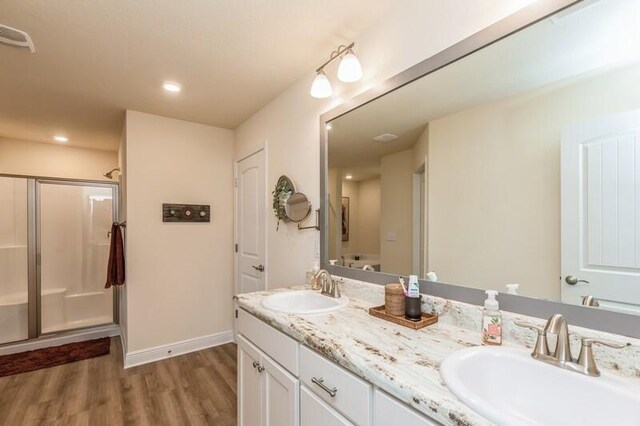 bathroom featuring a shower with door, double sink, oversized vanity, and hardwood / wood-style floors