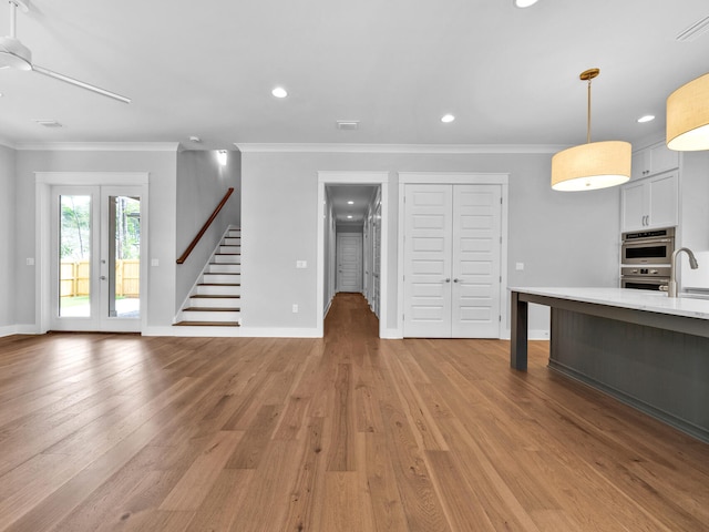 unfurnished living room with ornamental molding, ceiling fan, light hardwood / wood-style flooring, and sink