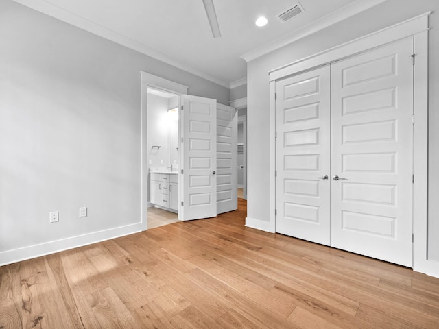 unfurnished bedroom featuring crown molding, light hardwood / wood-style floors, ensuite bath, and a closet