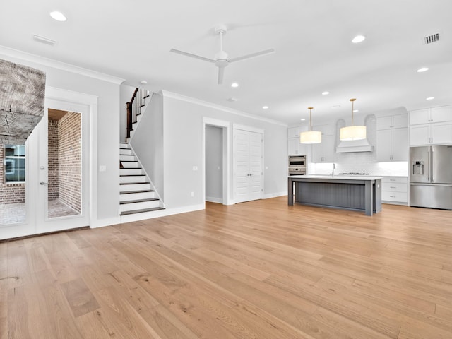 unfurnished living room featuring ceiling fan, light wood-type flooring, and crown molding