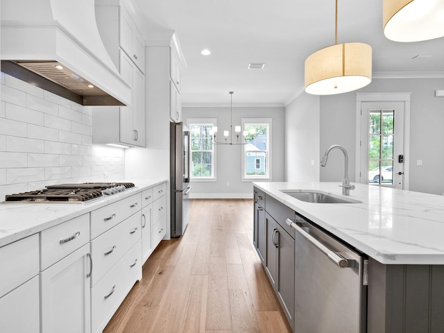 kitchen with sink, decorative light fixtures, white cabinetry, stainless steel appliances, and custom range hood